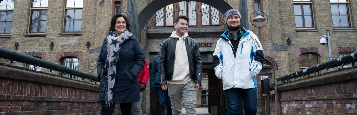 Drie personen, wandelend voor de Blokhuispoort in Leeuwarden